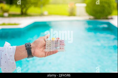 Hand holding Water Test Kit on blurred pool background, Hand holding a pool ph and chlorine tester, Person holding complete water test kit with Stock Photo