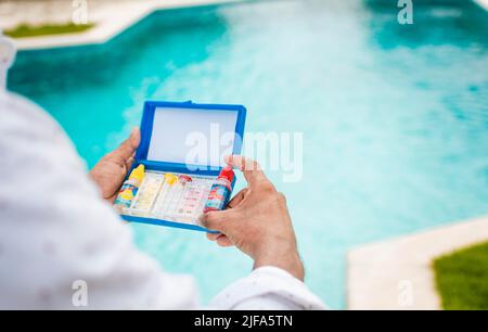 Hand holding Water Test Kit on blurred pool background, Hand holding a pool ph and chlorine tester, Person holding complete water test kit with Stock Photo