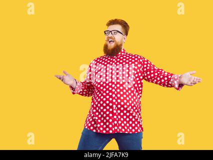 Funny fat man in polka dot shirt and glasses looks away with happy surprised face expression Stock Photo