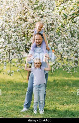 Happy young father with two daughters on a walk in the park. Portrait of a beautiful family Stock Photo