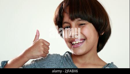 Child giving thumb up. Mixed race young boy winks and gives positive gesture Stock Photo