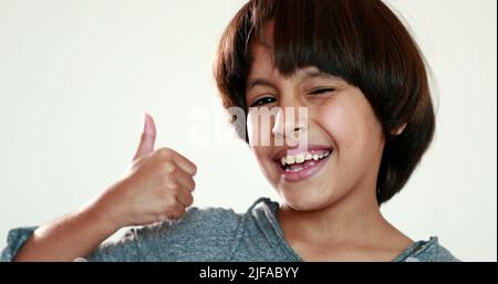 Child giving thumb up. Mixed race young boy winks and gives positive gesture Stock Photo