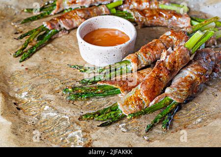 Baked green asparagus wrapped in crispy bacon. Light snack, side dish (garnish). Stock Photo