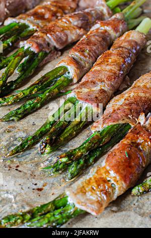 Baked green asparagus wrapped in crispy bacon. Light snack, side dish (garnish). Stock Photo