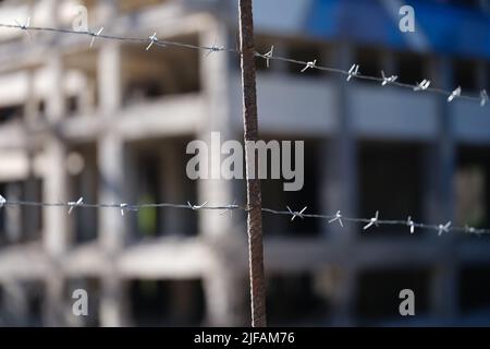 High level barbed wire fence in background of building Stock Photo