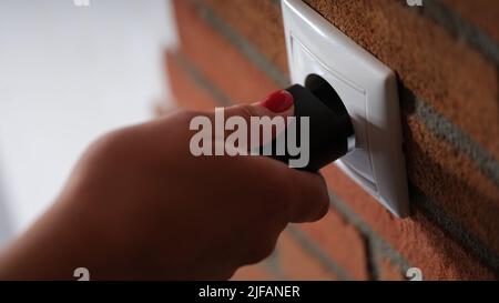 Closeup of hand inserting black plug into white socket Stock Photo