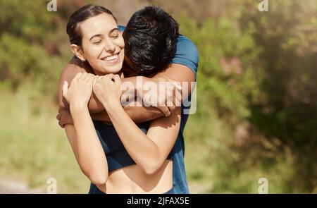 Affectionate young interracial couple taking a break from exercise and run outdoors. Loving man hugging arm around woman while motivating each other Stock Photo