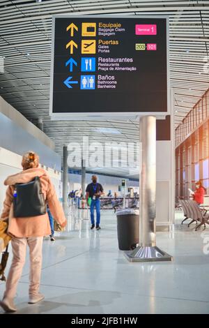 Directional signs in airport, recognizable people. Travel concept. Stock Photo