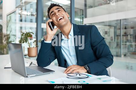 Young joyful mixed race businessman talking on a call using a phone and thinking alone at work. One hispanic male businessperson talking on a Stock Photo