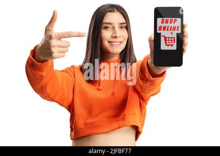 Cheerful young female holding a smartphone with text shop online and pointing isolated on white background Stock Photo