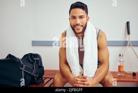 Portrait of a handsome man taking a break after a match. Happy young player sitting in a gym locker room. Fit, young player before a game. Confident Stock Photo