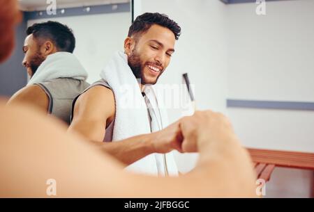 Cheerful friends gving each other a fist bump. Two players bonding and celebrating with a fist bump.Active men relaxing together in a locker room. Two Stock Photo