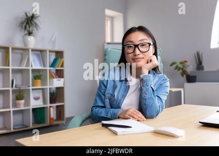 Portrait of young business woman in modern office, Asian looking at camera smiling. Stock Photo