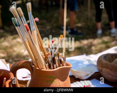 paint brushes in a ceramic jug, medieval painter's equipment on a table Stock Photo