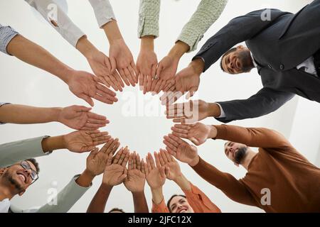 Diverse employees join hands engaged in teambuilding activity Stock Photo