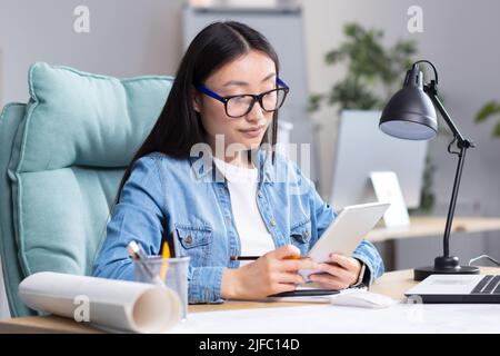 Young Asian woman designer working in office using tablet, working on drawing project. Stock Photo