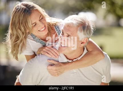 Closeup of an attractive young woman and her father outdoors. Young caucasian female and her senior father bonding outside in the garden on a sunny Stock Photo