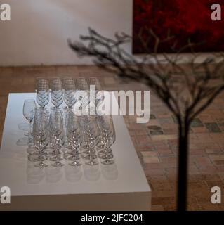 sparkling crystal wine glasses arranged in a row on a table with a white tablecloth ready for wine tasting, matrix, wine barrel in background Stock Photo