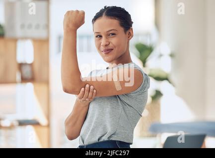 Young happy mixed race woman showing and holding her arm with a bandaid after getting a vaccine. Beautiful and confident young woman playing a showing Stock Photo