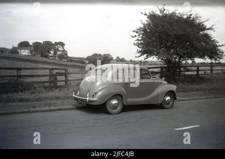 1950s, historical, rear side view of an Austin car of the era, an A40 Devon saloon parked on a country road, England. Produced between 1947 and 1952, the car was the first post-war saloon made by the Austin Motor Company. With a mix of old and newer technologies, the motorcar was notable for its old style, conservative appearance. Stock Photo