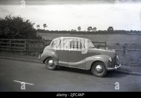 1950s, historical, side view of an Austin car of the era, an A40 Devon saloon parked on a country road, England. Produced between 1947 and 1952, the car was the first post-war saloon made by the Austin Motor Company. With a mix of old and newer technologies, the motorcar was notable for its old style, conservative appearance. Stock Photo