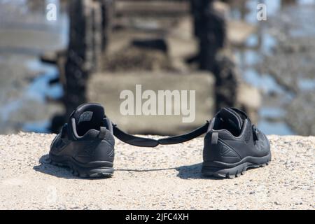 The abandoned shoes at the rim of the ending of a demolished way Stock Photo
