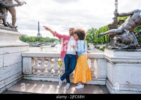 Black cheerful happy couple in love visiting Paris city centre and Eiffel Tower - African american tourists travelling in Europe and dating outdoors Stock Photo