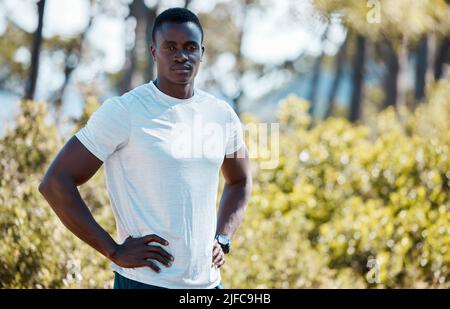 Young fit active african black male runner wearing sportswear and a watch standing with his hands on his hips looking serious and confident after a Stock Photo