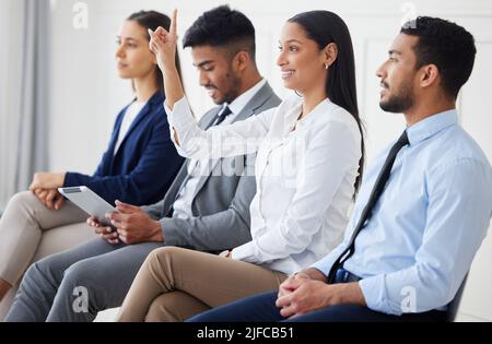 Mixed race businesswoman raising finger to ask question in interview. Diverse businesspeople team in office seminar. Group of applicants and Stock Photo
