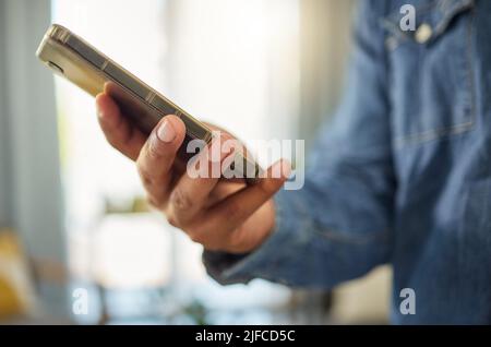 Hands of a man using his cellphone to send a text message. Bachelor connected to the internet with his smartphone. Always online using apps on his Stock Photo