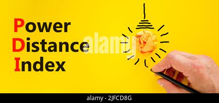 PDI power distance index symbol. Concept words PDI power distance index on yellow paper on a beautiful yellow background. Businessman hand. Business P Stock Photo