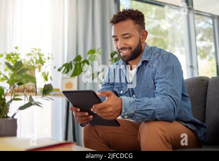 Handsome bachelor reading on his digital tablet. Happy bachelor enjoying his day at home relaxing. Always connected to the online world with his Stock Photo