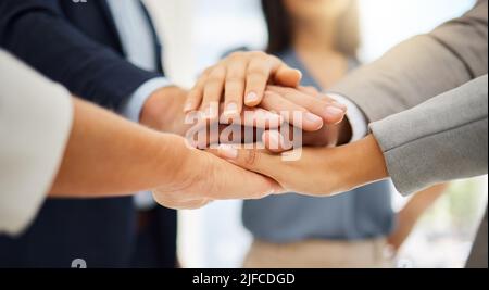 Closeup of a group of diverse businesspeople joining their hands together in a huddle. Ambitious colleagues staying motivated and inspired while Stock Photo