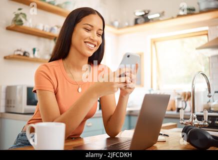 Young beautiful happy mixed race businesswoman using a phone while working from home. Content hispanic woman using social media on her cellphone while Stock Photo