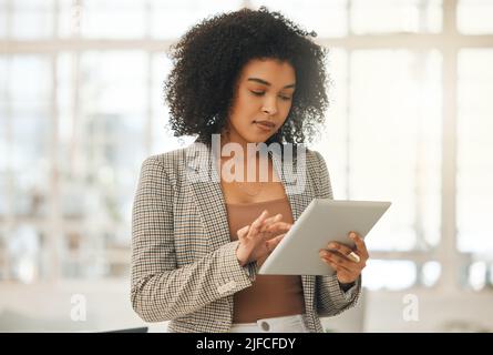 Young businesswoman using a digital tablet. Focused designer standing in her agency. Creative entrepreneur working on a wireless device. Young Stock Photo