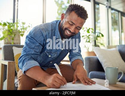 Happy bachelor signing a contract. Man filling out insurance documents. Handsome young man filling out banking papers. Hispanic young man filling out Stock Photo