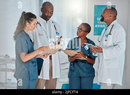 Group of diverse doctors having a meeting together working at a hospital. Team of medical professionals talking while planning their day at work at a Stock Photo