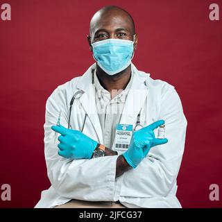 African american covid doctor holding corona vaccine and needle while wearing surgical face mask. Portrait of black physician holding drug vial and Stock Photo