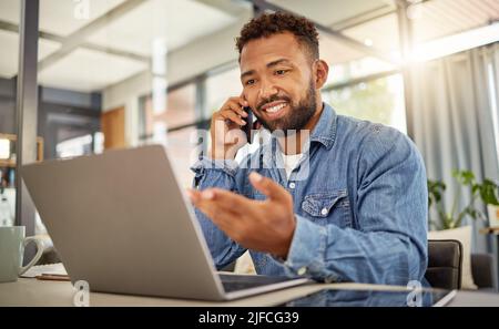 Remote entrepreneur working from home on his laptop. Virtual businessman making a phone call on his cellphone. Confident businessman telework from Stock Photo