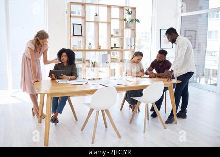 Group of diverse businesspeople having a meeting at a table in an office. Business professionals talking and planning together at work. Male and Stock Photo