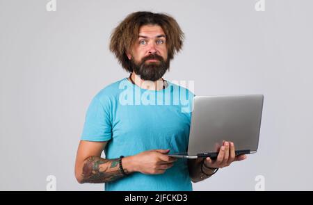 Bearded man in t-shirt with laptop computer. Education, studying and student life. Stock Photo