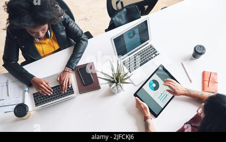 Two businesswoman working together using digital tablets and laptops from above. Two businesswoman planning together during a meeting using a digital Stock Photo