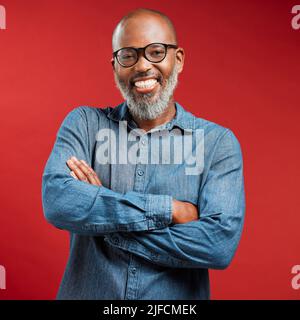 Mature African American man wearing glasses and smiling while posing against a red background. Black male happy with his new spectacles frame at his Stock Photo