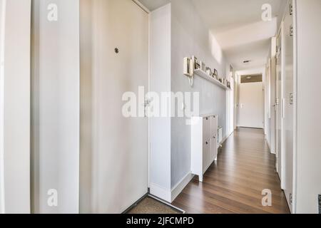 Interior of narrow corridor with telephone and radiator hanging on wall against stairway in daylight Stock Photo