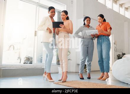 Group of businesswomen talking and using a digital tablet and report together at work. Serious businesspeople talking and planning while standing in Stock Photo