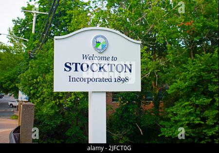 Wooden welcome sign to suburban town of Stockton, New Jersey, amid a green background of trees and bushes -01 Stock Photo