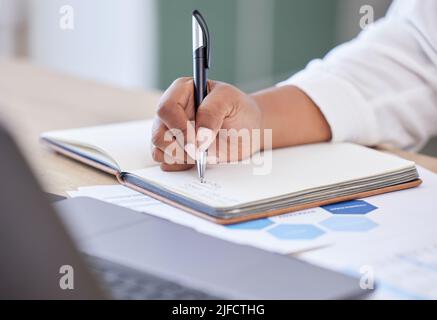 Businessperson writing in a notebook working in an office at work. Closeup of a business professional holding a pen and taking notes in a diary Stock Photo