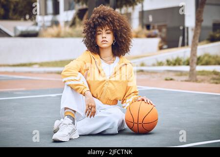 Mixed race woman posing on a basketball court. Beautiful basketball player posing confidently outside Stock Photo