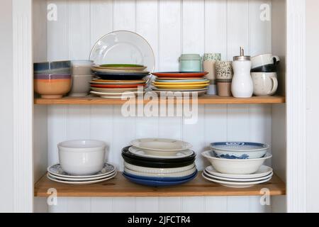 Wooden kitchen cabinet with ceramic plates and pots in kitchen in