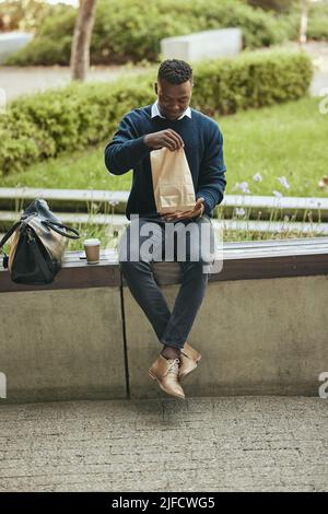 Businessman outside during his lunch break. Man taking a break from the office. Man opening his lunch Stock Photo